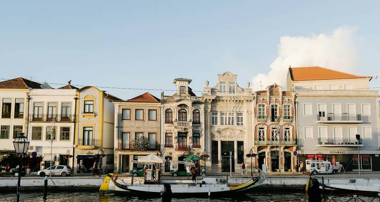 Elegantes casas adosadas en tonos pastel bordean un canal donde está amarrado un barco tradicional.
