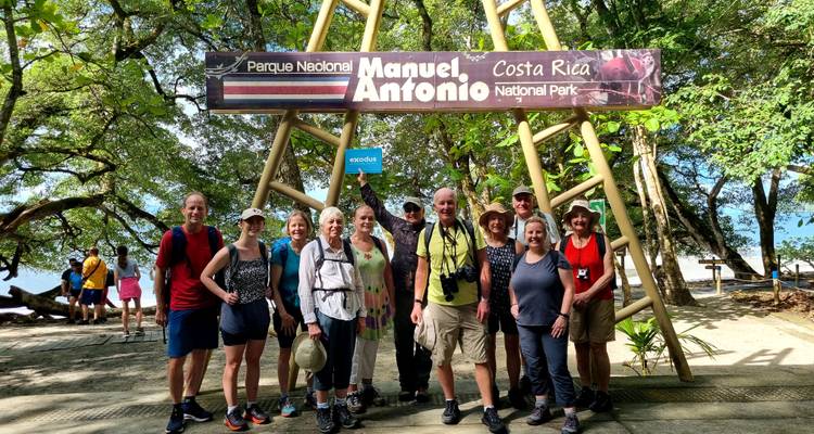 Reisegruppe, die sich unter dem Eingangsschild des Manuel-Antonio-Nationalparks posiert.