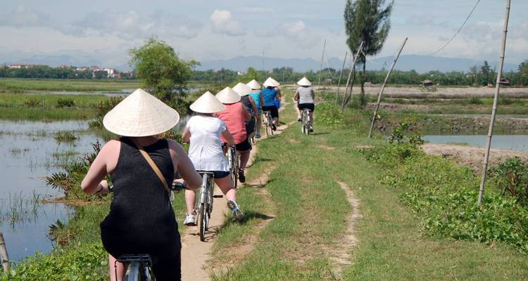 Group of people cycling in rural Vietnam wearing traditional hats