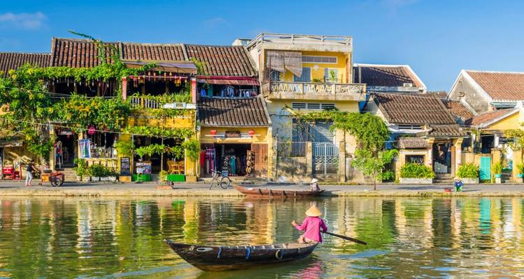 Colorful riverside town with traditional architecture and a person rowing a boat.