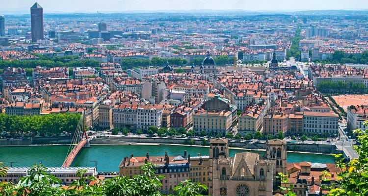 Vue panoramique d'une ville traversée par une rivière, avec des toits en tuiles rouges.