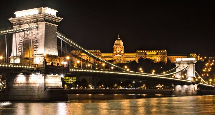 Puente de las Cadenas de Budapest iluminado por la noche con el Castillo de Buda al fondo.