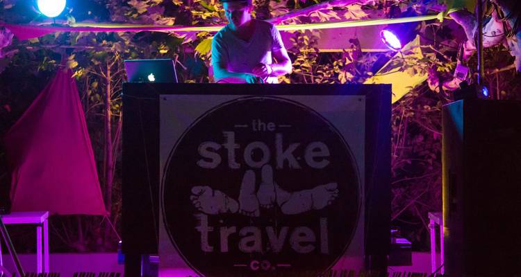 DJ playing music at night with colorful lights.