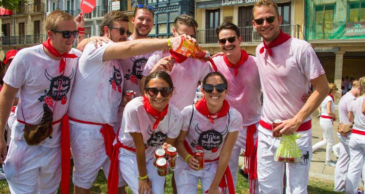 Group of people celebrating, wearing white clothes with red scarves.