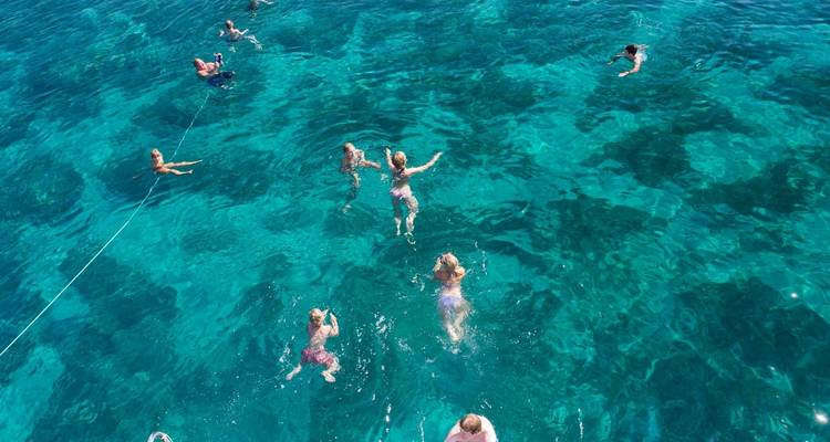 Vista aérea de personas nadando en agua azul cristalina.