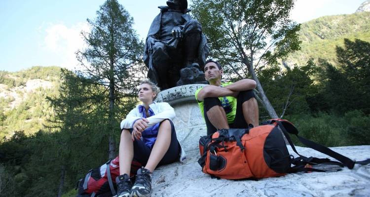 Dos excursionistas descansando junto a una estatua de montaña.