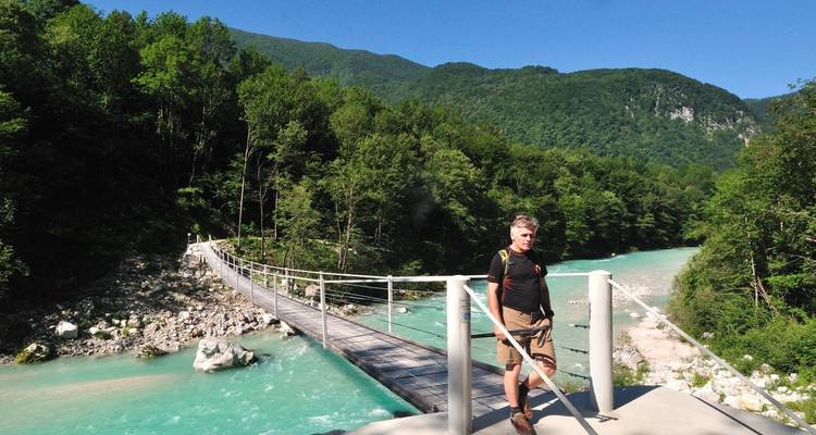 Randonneur sur un pont suspendu en bois au-dessus d'une rivière.
