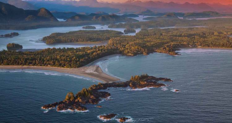 Vista aérea de bahías escarpadas, playas arenosas y penínsulas boscosas a lo largo de la costa del Pacífico de la Isla de Vancouver al atardecer.