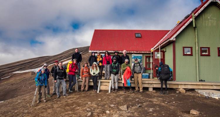 Groupe de personnes posant devant des cabanes colorées dans un cadre montagnard.