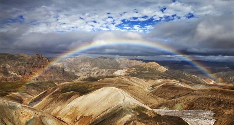 Scenic mountain view with a prominent rainbow arching across the landscape.