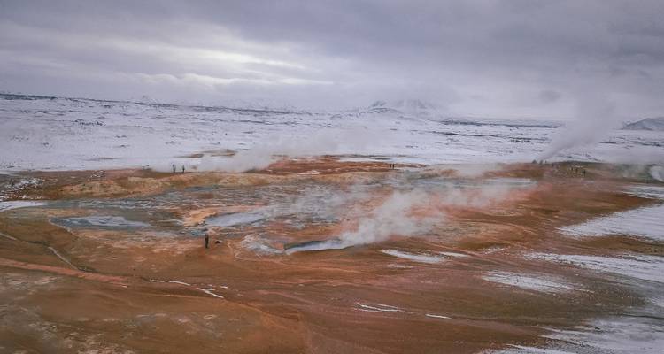 Vista amplia de un área geotermal con vapor elevándose desde el suelo.