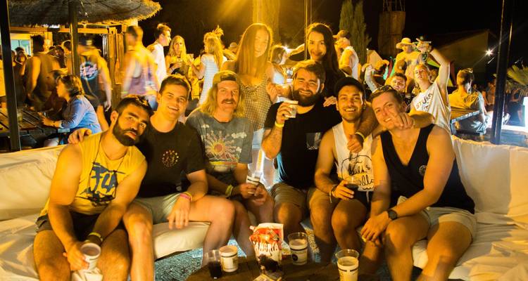 Groupe d'amis posant à un festival du soir avec des boissons.