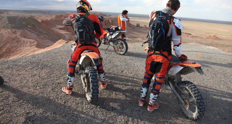 Motorradfahrer betrachten die Wüstenlandschaft von einem hohen Punkt aus.