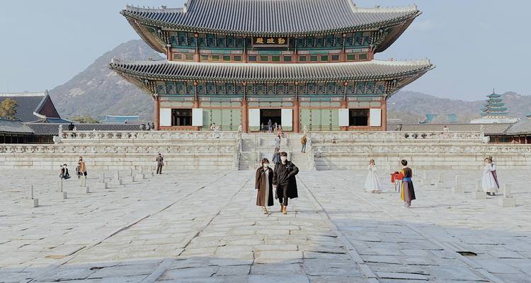 Palais royal coréen traditionnel avec des visiteurs se promenant dans l'enceinte.