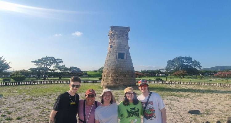 Grupo de personas posando junto a una estructura de piedra antigua.