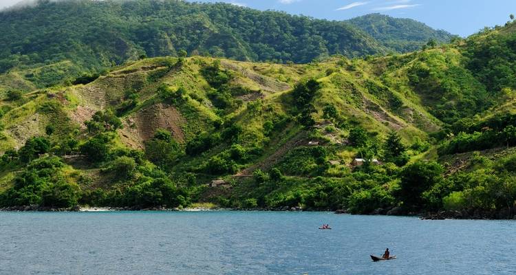 Scenic view of a lake with hills covered in greenery.