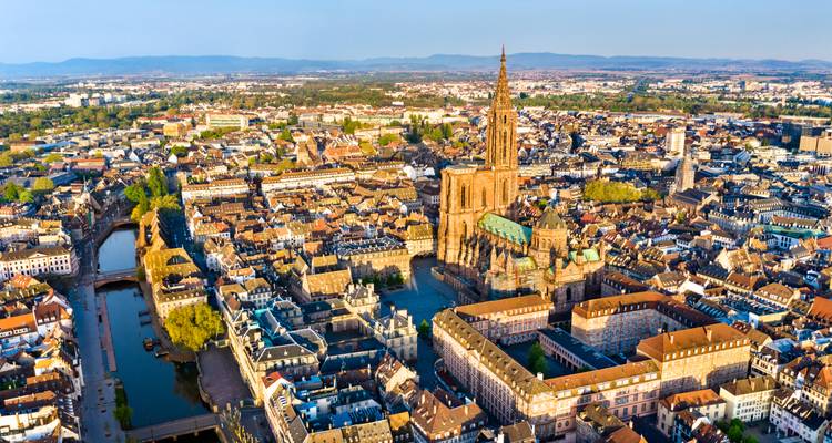 Panoramic aerial of a medieval cathedral dominating a dense old-town cityscape crossed by canals.