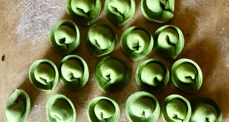 Frisch gemachte grüne Tortellini auf einer bemehlten Oberfläche.