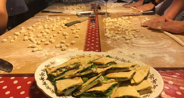 Menschen, die Gnocchi zubereiten, mit einem Teller Sandwiches im Vordergrund.