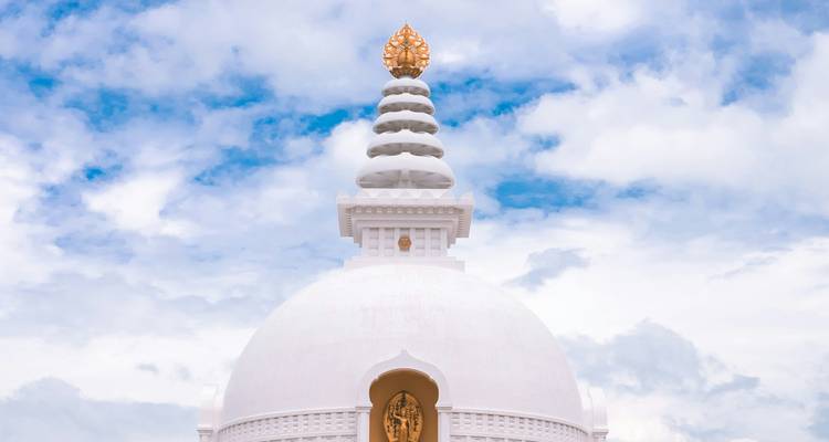 Une pagode de la paix d'un blanc immaculé s'élève vers un ciel partiellement nuageux.