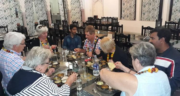 Reizigers die samen een traditionele Indiase thali-maaltijd delen rond een tafel in een versierd restaurant.