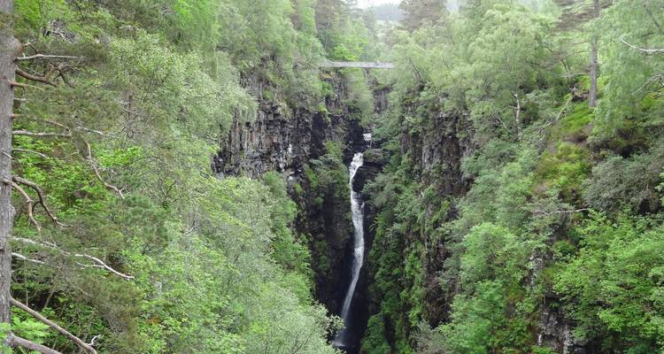 Wasserfall versteckt zwischen steilen Klippen und üppigen Bäumen.