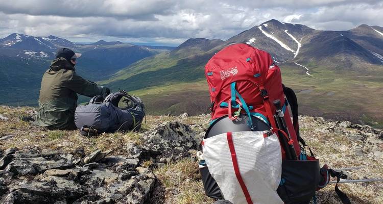 Hikers resting with backpacks on a mountain ridge.
