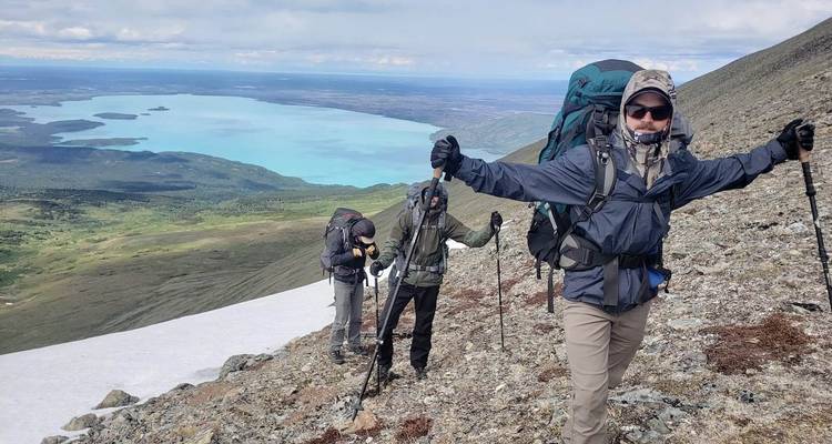 Hikers making their way up a snowy mountain with a lake view.