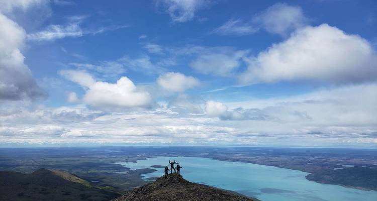 Hikers raising hands in triumph on a mountain summit with a wide view.