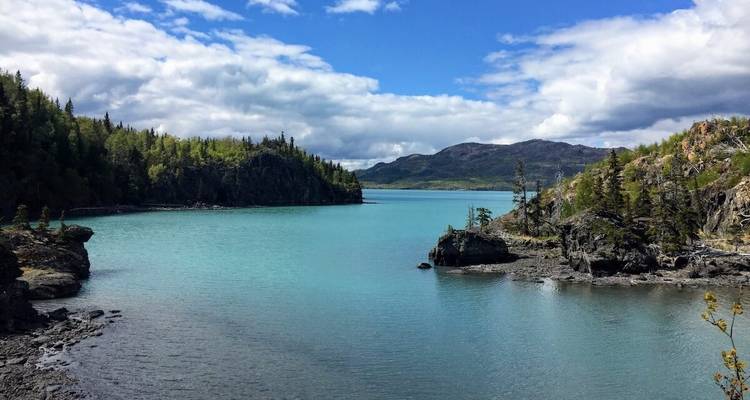 A serene lake surrounded by lush greenery and mountains.