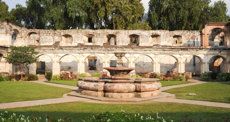 Des ruines de couvent colonial bien entretenues présentent une fontaine centrale ornée entourée de corridors voûtés et de pelouse soignée.
