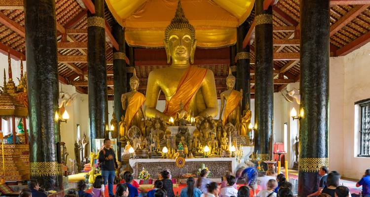 Intérieur d'un temple avec une grande statue de Bouddha et des visiteurs.