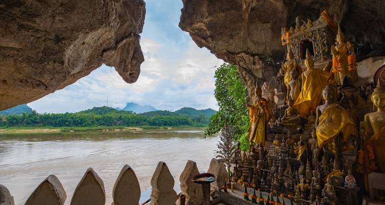 Vue depuis une grotte avec de nombreuses statues de Bouddha surplombant une rivière.