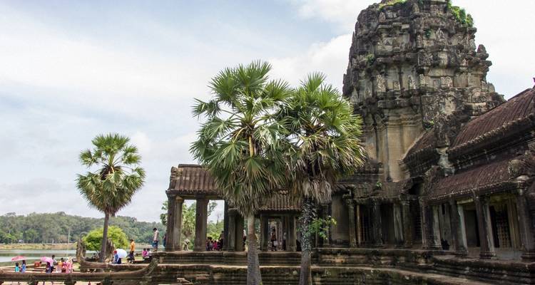 Ruines du temple d'Angkor Wat entourées de verdure luxuriante et de visiteurs.