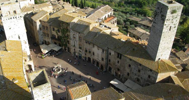 Vista aérea de la plaza medieval de San Gimignano con torres de piedra y multitudes abajo