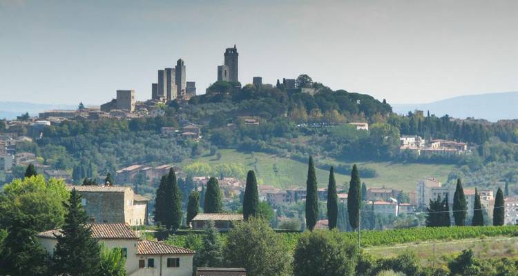 Silueta distante de las icónicas torres medievales de San Gimignano elevándose sobre el campo verde