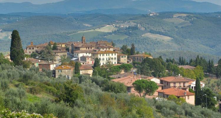 Pueblo toscano en la cima de una colina rodeado de olivares y colinas verdes escalonadas