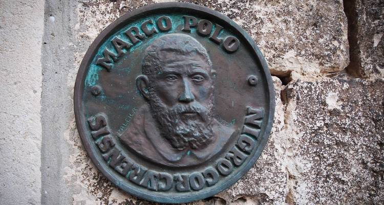 Plaque de bronze de Marco Polo sur un vieux mur de pierre.