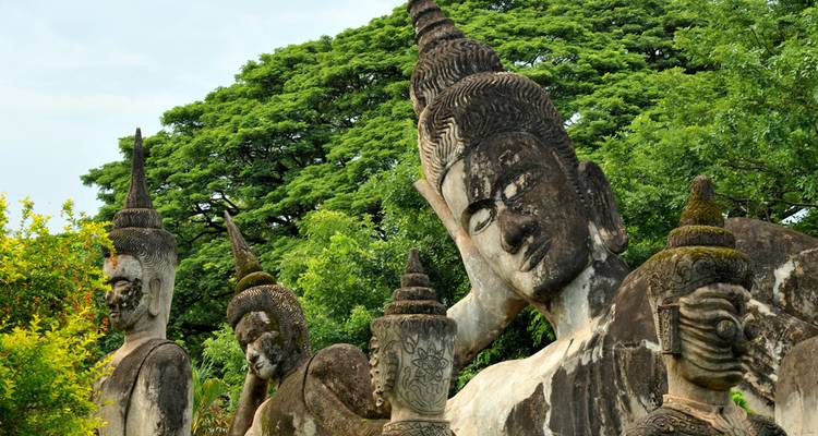 Große, moosbedeckte Buddha-Statuen in einem Freiluftskulturskulpturenpark, umgeben von üppig grünen Bäumen.