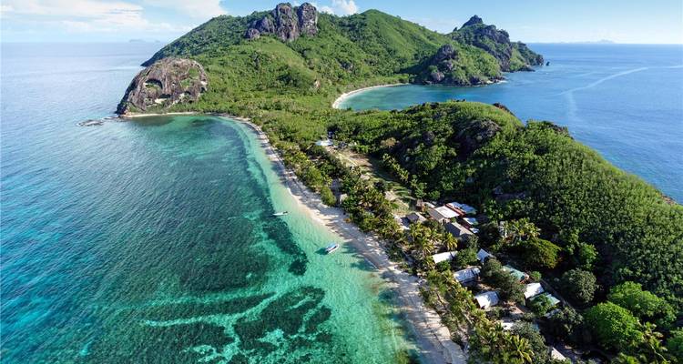 Aerial panorama of a tropical island with dramatic green peaks, fringing reef and turquoise lagoons.