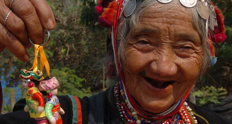 Elderly woman holding decorative keychains, wearing traditional attire.