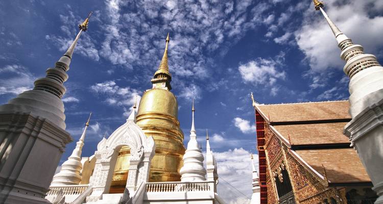 Templo con estupas doradas y blancas contra un cielo azul.