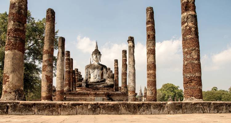 Ruines historiques avec une grande statue de Bouddha entourée de piliers.