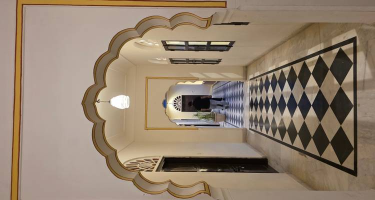 Elegante marmeren gang met geschulpte bogen en zwart-wit geblokte vloer in een erfgoed haveli.