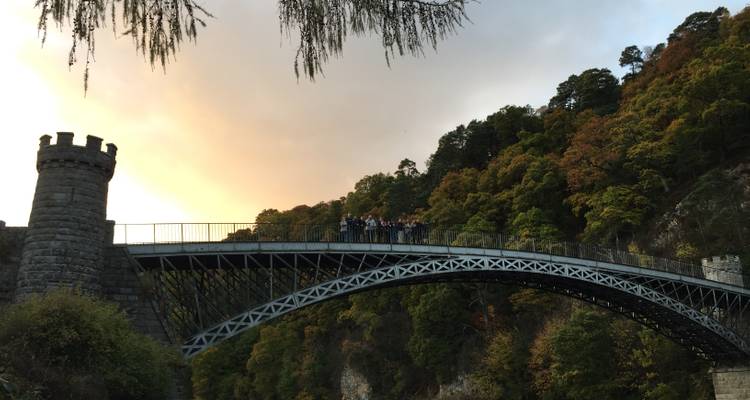 Grupo de personas en un puente con la puesta de sol al fondo.