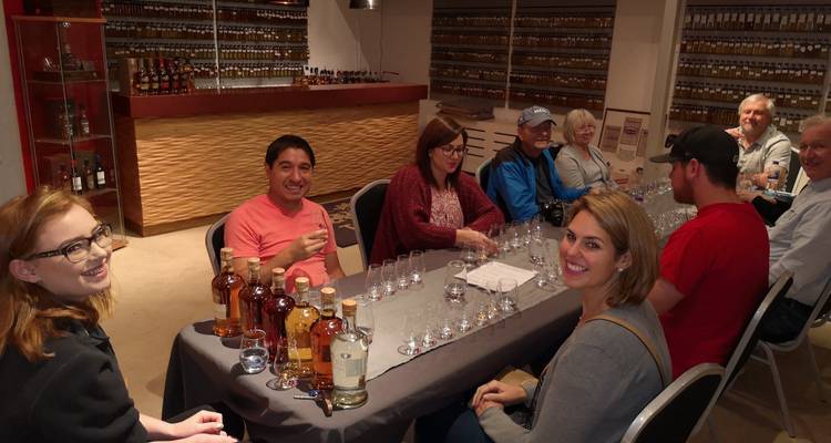 Group of people at a tasting event surrounded by whisky bottles.