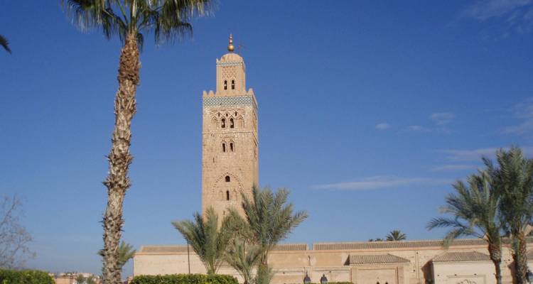 Das Minarett der Koutoubia-Moschee erhebt sich über Palmen gegen einen klaren blauen Himmel von Marrakesch.