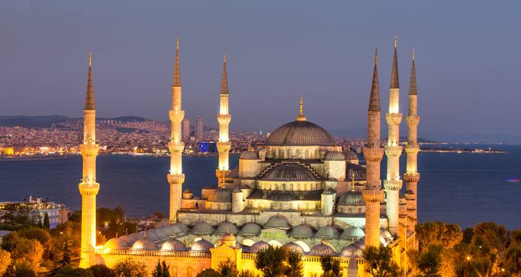 Eine berühmte Moschee in der Abenddämmerung mit der Stadt und dem Wasser im Hintergrund.