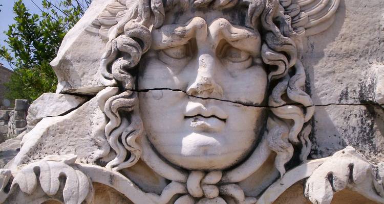 Eine Nahaufnahme eines antiken Steinreliefs mit einem mythischen Gesicht.