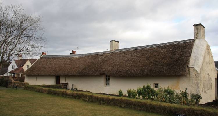 Traditionelles Reetdachhaus mit bewölktem Himmel.